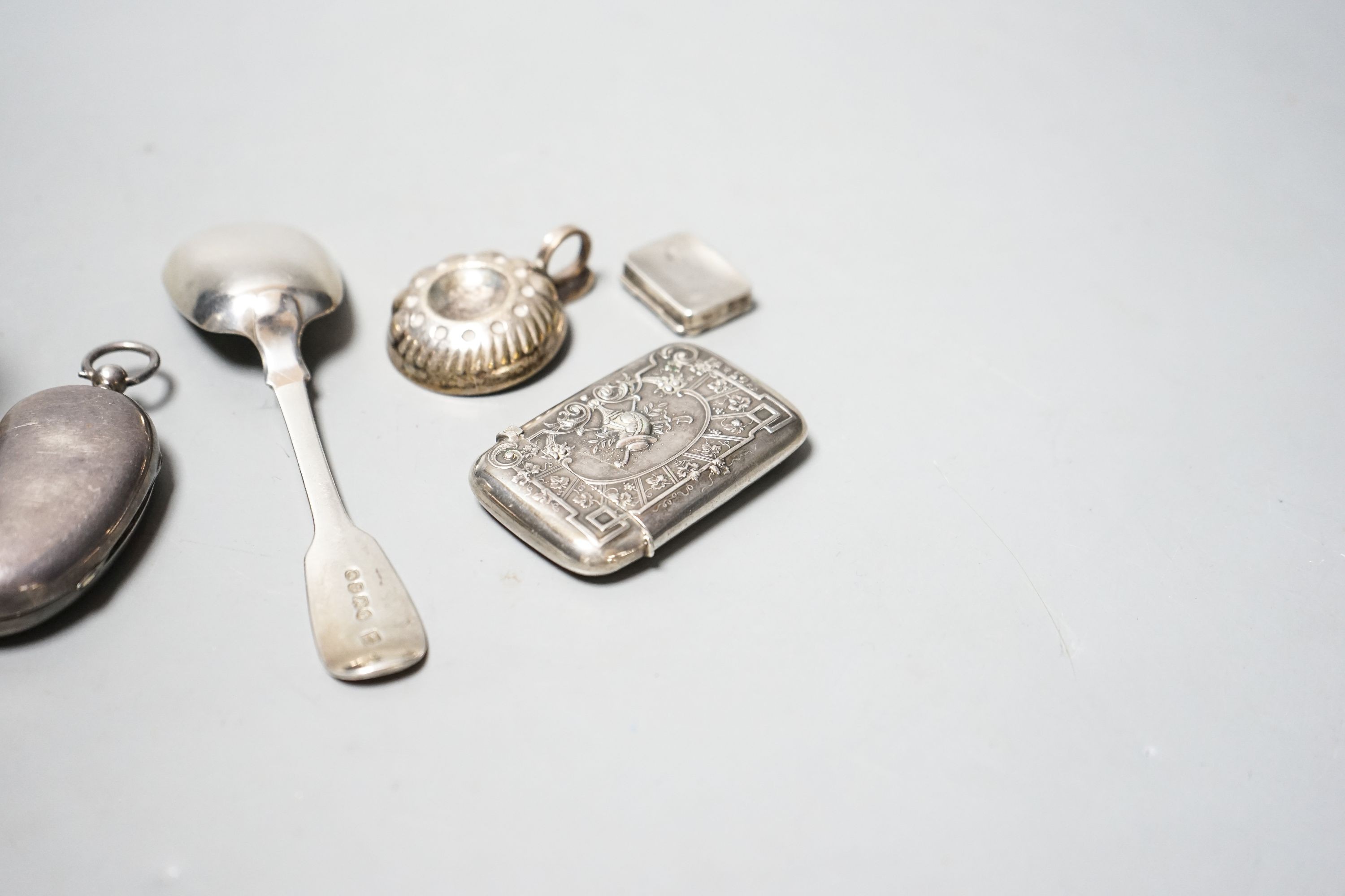 A George V silver twin sovereign kidney shaped case, 65mm, a silver spoon, silver tot , silver pill box, a German 800 vesta case and a plated small taste vin.